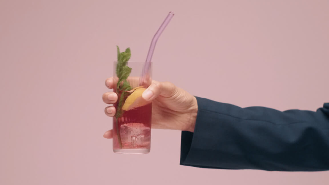 Hand holding glass of a drink, symbolising vacation mood and that you can sign leave application with Oneflow. 