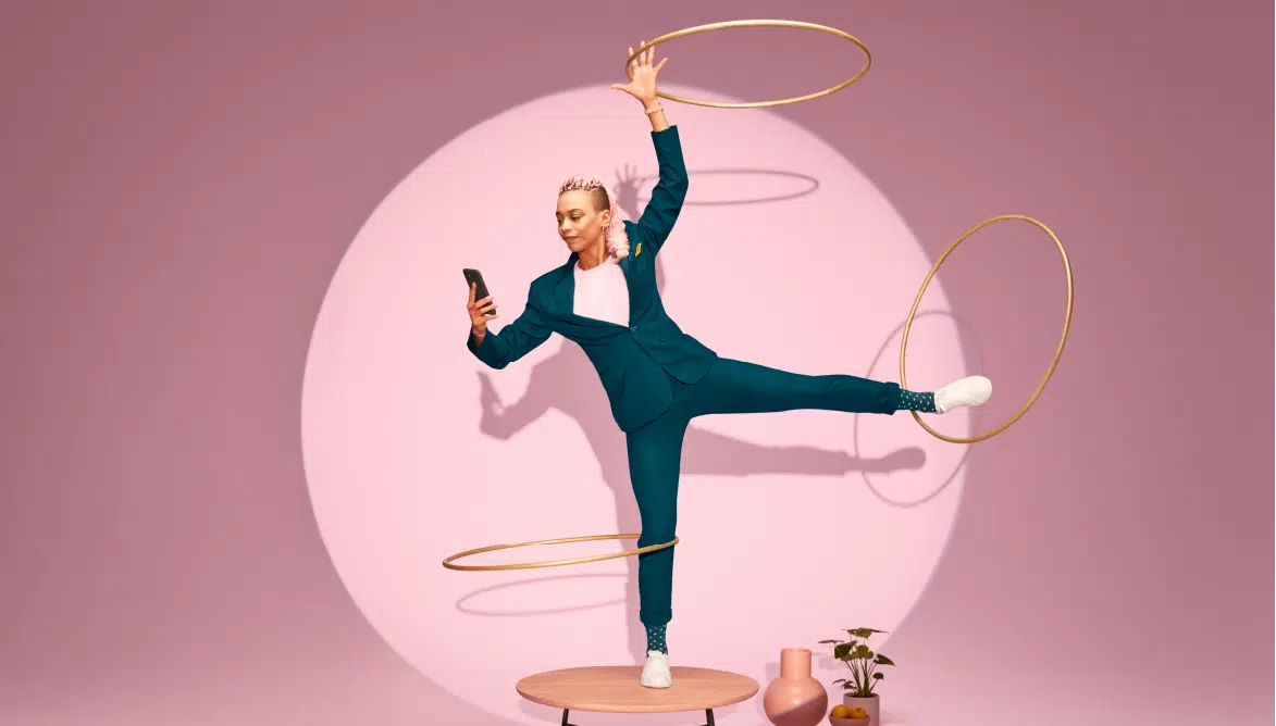 Woman looking at her phone while doing hula hoop with her other arm and legs. Image symbolising the flow of a data driven sales strategy and approach.