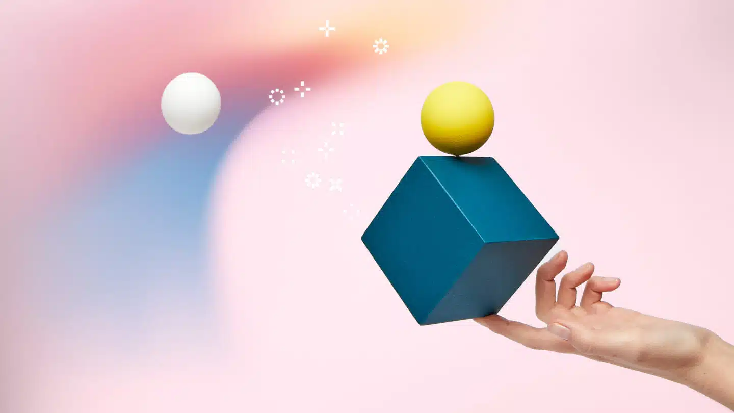 Hand balancing green cube on index finger with small yellow ball on top – blog on top 10 best AI writing tools for 2023 