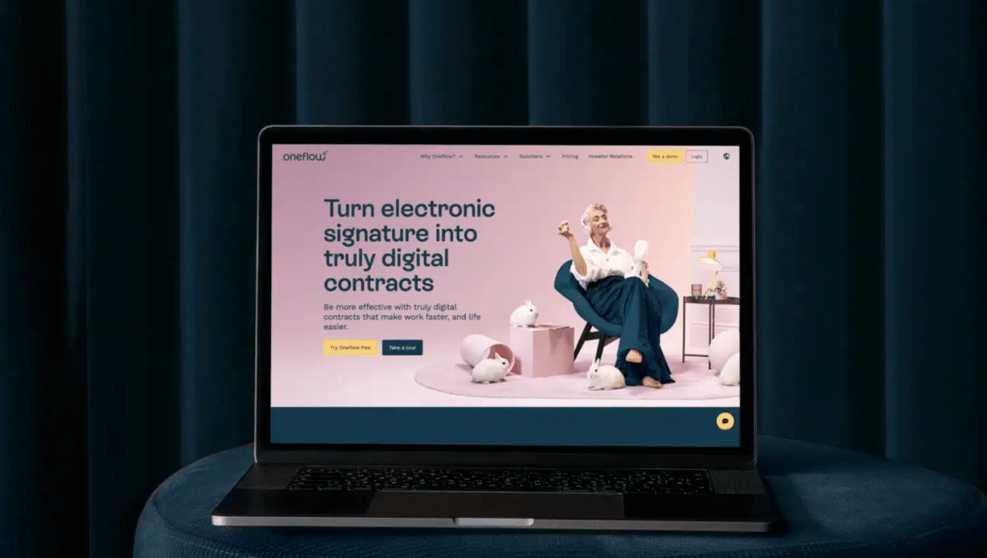 Bärbar dator på en blå/grå soffa med Oneflow-webbplats - blogg om hur elektroniska signaturer kan gynna hybridarbetarea