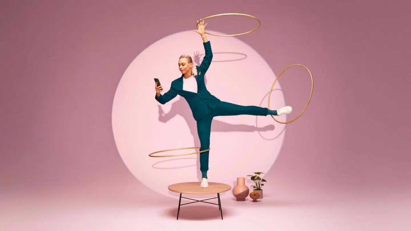 A woman balancing on one leg with several hoops, signing contracts with a qualified electronic signature (QES) on her phone.